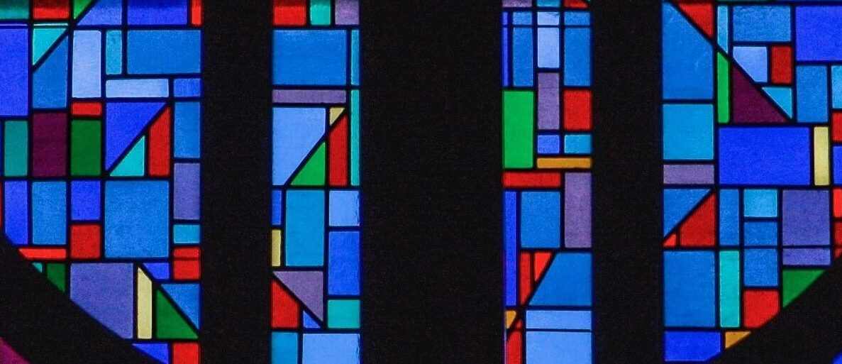 A wooden cross surrounded by a geometric mosaic stained glass